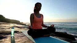 Serene latin american woman meditating near the ocean sitting on her mat Stock Footage