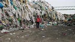 Worker walking past huge piles of garbage at waste disposal dump Stock Footage