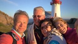 A big happy family takes a selfie or Uses Phone Video Call Camera on the seacoast with an old lighthouse Stock Footage