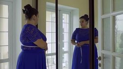 Fat girl in a blue dress in front of a mirror Stock Footage
