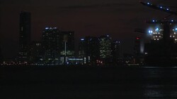 WIDE ANGLE OF MIAMI HARBOR AND SKYLINE. SEE LIGHTS ON HARBOR CRANES AND BOATS. SEE TALL OFFICE BUILDINGS AND SKYSCRAPERS. END OF SUNSET. SHOT BEGINS AND ENDS OUT OF FOCUS. EFFECT. Stock Footage