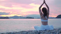 Happy young woman relaxing by practicing yoga on the beach at sunset, Sunrise background. Fitness, sport, yoga and healthy lifestyle concept. Stock Footage