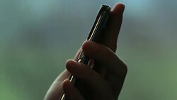 Candid 4K clip of hand holding cellphone while on a moving train with background landscape in motion. Person holds smartphone while commuting Stock Footage