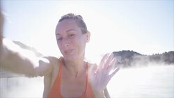 Woman relaxing in hot spring pool in Iceland and takes selfie portrait bathing Stock Footage