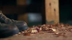 Wood shavings fall to the floor of a workshop where a person in heavy-duty work boots is standing. Stock Footage