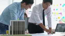 Architects male and Businessman are paper blueprint and building model. Business man suggest idea to designer at modern office. concept of construction, architecture, development and creative. Stock Footage