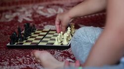 Hands close-up of a child arranging white chess pieces on the chessboard Stock Footage