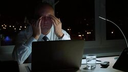 Tired businessman rubbing eyes while executive working by notebook in night office Stock Footage