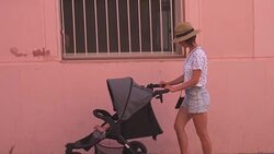 Stylish mother with baby stroller walking in street during vacation Stock Footage