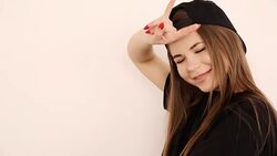 teenage girl in trendy hip hop clothes and cap posing against white wall Stock Footage