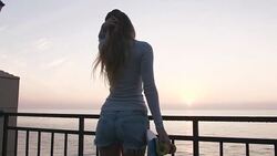 Beautiful and fashion young woman posing with a skateboard during sunrise at seafront Stock Footage