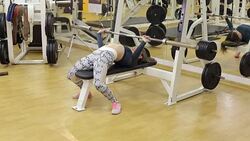 Sporty girl doing an exercise with a bar in the supine position in the gym. Stock Footage
