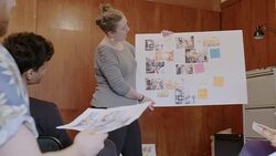 Female creative designer leading meeting, discussing photograph proofs in office Stock Footage