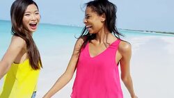 Laughing African American Asian Chinese girls on beach Stock Footage