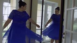 Fat girl in a blue dress in front of a mirror Stock Footage
