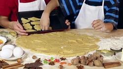 Two kids lay out the dough for xmas cookies to baking tray Stock Footage