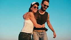 young woman and man enjoying the sunset in front of a blue sky Stock Footage