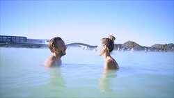 Geothermal spa. Young couple relaxing in hot spring pool in Iceland. people enjoying bathing in a blue water lagoon Icelandic tourist attraction, Video SLOW MOTION Stock Footage