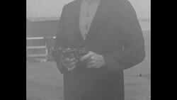 In the 1930s one man fires revolvers, another man fires machine gun from inside car News Clip