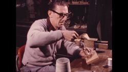 1970s: Man winds thread around stuffed bird mounted on board Stock Footage