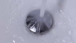 Closeup of tap water flowing into stainless steel drain Stock Footage