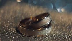 Wedding rings lying on shiny surface shining with light close up macro Stock Footage