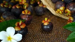 Top view of fresh delicious harvested mangosteens on wooden table. Thai organic purple fruit in the basket. Exotic natural blurred background with tropical flower. Healthy food and eating concept. Stock Footage