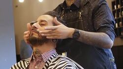 Barber applying aftershave to customer in salon Stock Footage