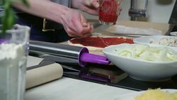 Young woman spreading tomato sauce on dough Stock Footage