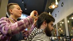 Bearded young man getting haircut by barber Stock Footage