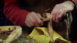 A scraping tool is used to shape a curved piece of wood in a workshop. Stock Footage