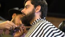 Barber trimming beard of customer using scissors Stock Footage