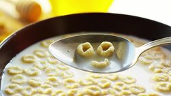 on a sunny day in the garden pours cereals in a cup where the cereals falls in slow motion . concept of healthy food and breakfast of milk and bisquits or cookies and cereals. bio food Stock Footage
