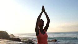 Tranquil female meditating sitting on mat with eyes closed next to the beach Stock Footage