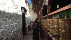 Pilgrims spin prayer wheels in Ramoche Temple. Stock Footage