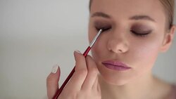 Professional make up artist correcting finishing eye shadows application blending color with brush. Woman model getting new image indoors beauty salon slow motion rack focus. Female beauty concept Stock Footage