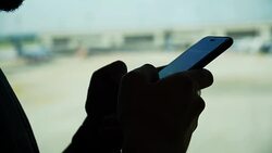 Young Asian man using mobile phone touchscreen and talking on phone. working on the phone, in the background of a Airport , planes, Concept: new business, travel, communication. Stock Footage