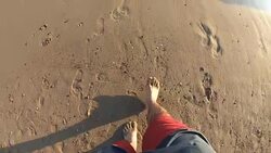 Feet with wave on sandy beach top view slow motion Stock Footage