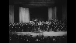 United States, c.1951: An orchestra plays to the beat of the conductor during a concert Stock Footage