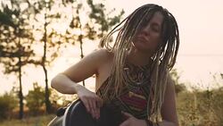 Beautiful young hippie woman with dreadlocks playing on djembe. Funky woman drumming in nature on an ethnic drum at sunset or sunrise Stock Footage