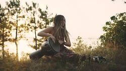 Beautiful young hippie woman with dreadlocks playing on djembe. Funky woman drumming in nature on an ethnic drum at sunset or sunrise Stock Footage