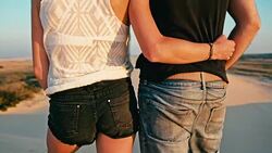young woman and man enjoying the sunset on the peak of one of the desert sand dune Stock Footage