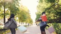 Dolly shot of happy women friends walking and running along street with paper bags turning and laughing having fun enjoying leisure time. Shopping and friendship concept. Stock Footage