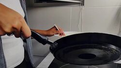 Woman spreading pancake dough on the frying pan Stock Footage