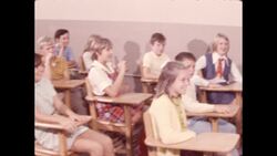 1970s: Students sitting at desks smile as man shows them snake Stock Footage