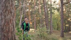 Caring dad is hiking with his little male child in forest walking among trees with backpacks during autumn weekends. Nature, people and family concept. Stock Footage