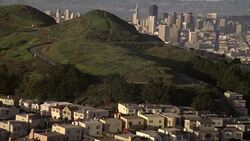AERIAL OF RESIDENTIAL AREA OF SAN FRANCISCO. SEE HOMES, HOUSES, OR TOWNHOUSES OR CONDOMINIUMS. CAMERA PANS OVER HILL BEHIND HOUSES TO SEE DOWNTOWN SAN FRANCISCO SKYLINE IN HORIZON. SEE FINANCIAL DISTRICT. Stock Footage