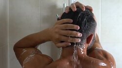Guy taking shower, enjoying warm drops on his body, wasteful water consumption Stock Footage