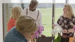 Instructor helping active senior students learning to arrange orchid flowers Stock Footage