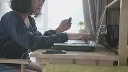 Young woman with credit card and laptop paying bills online in her room. Stock Footage